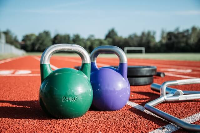Imagem de halteres em um campo de treinamento esportivo, com a legenda: O fortalecimento dos músculos da coxa é essencial no tratamento da síndrome de Osgood-Schlatter.

Foto por Alora Griffiths, do Unsplash.
